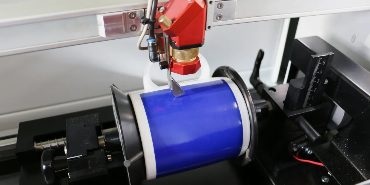 Trotec laser engraver with rotary attachment etching ceramic mug using CO₂ laser technology