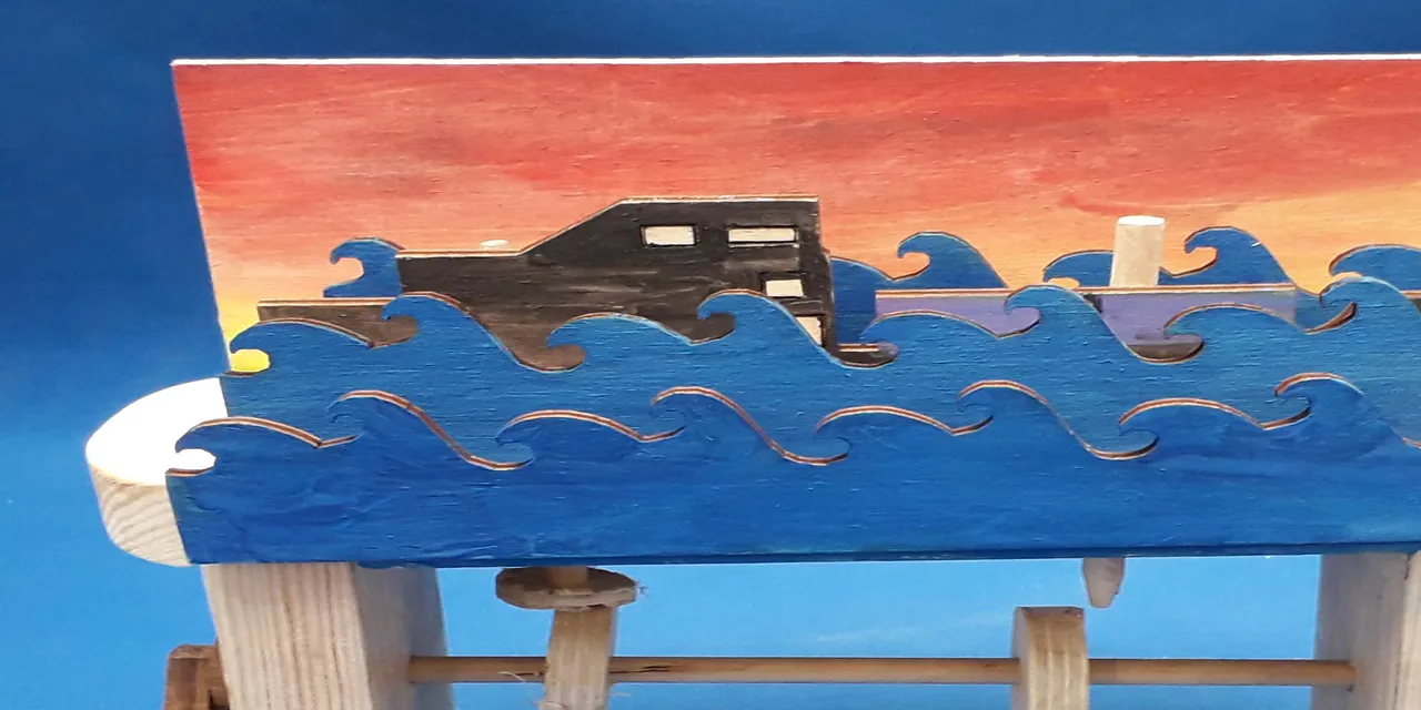 Laser-cut wooden automaton with painted waves and boat, likely created using Trotec CO₂ laser cutter