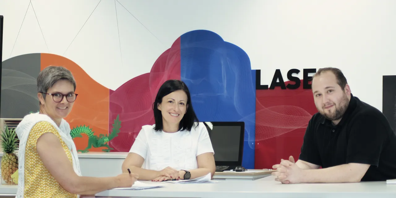 Trotec team members meeting in modern office with laser cutting graphics in background