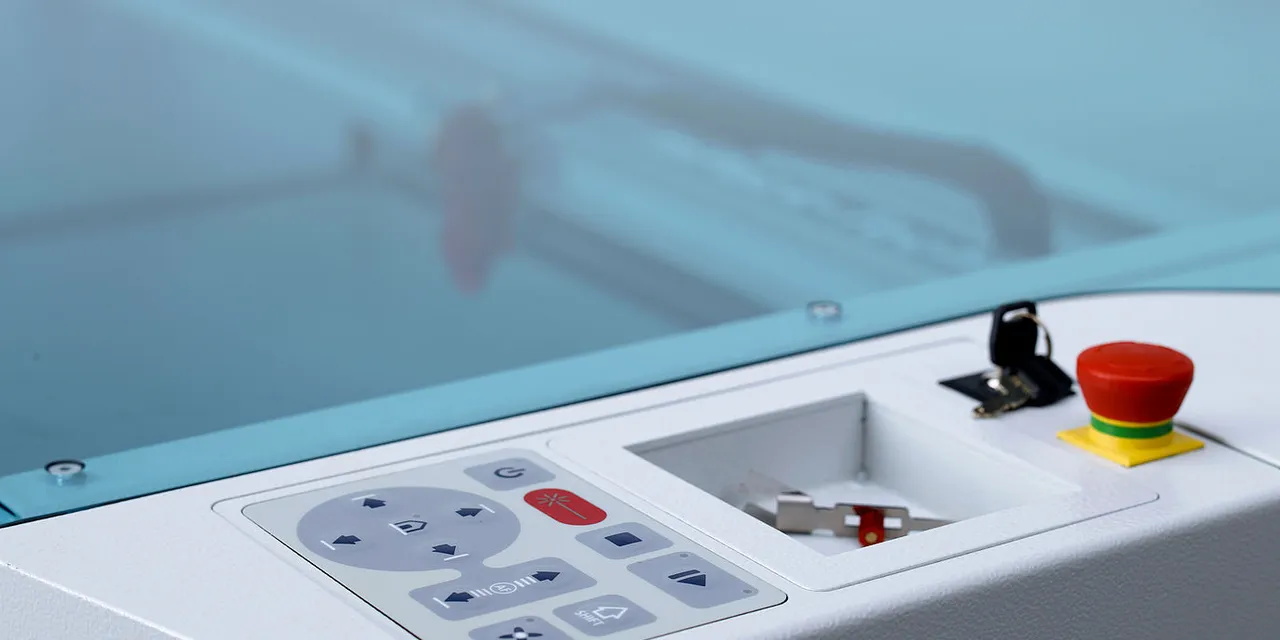 Close-up of Trotec Speedy series CO₂ laser cutter control panel with emergency stop button and keys