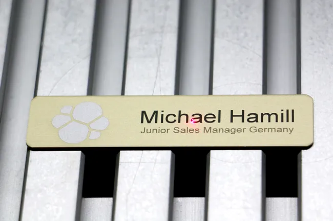 Trotec laser engraver marking a metal name badge with text and logo