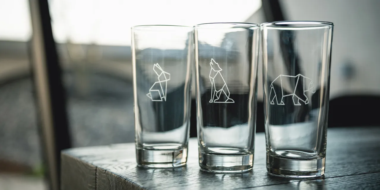 Glass cups with animal designs engraved using Trotec laser engraver on wood table
