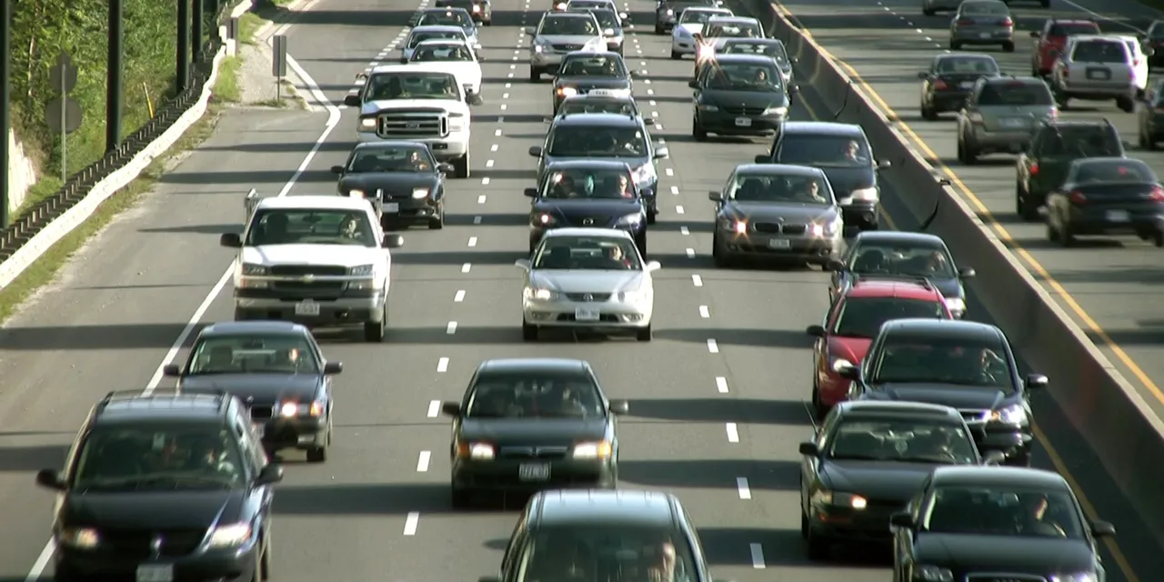 Heavy traffic on multi-lane highway with cars moving in both directions during daylight