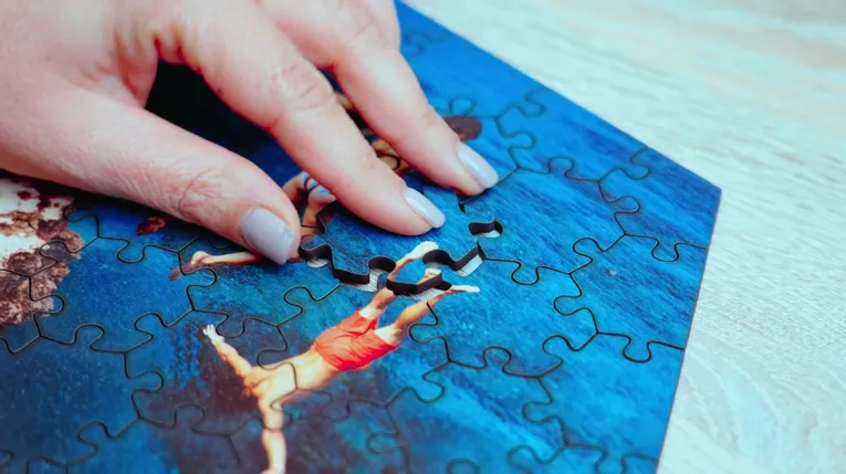 Hand assembling custom photo puzzle cut with Trotec laser cutter on wooden table