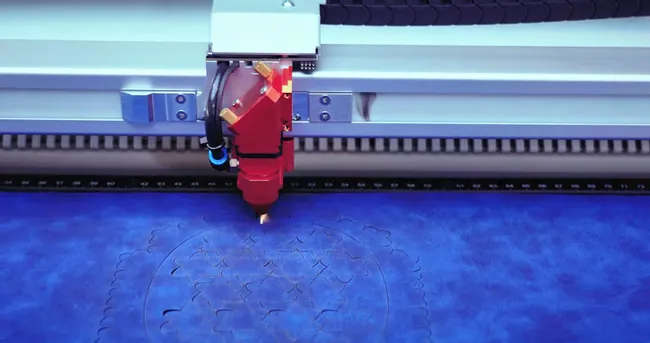 Trotec laser cutter engraving intricate floral pattern on blue material with CO₂ technology