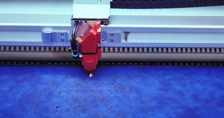 Trotec laser cutter engraving intricate floral pattern on blue material with CO₂ technology
