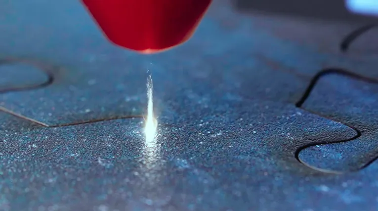 Trotec laser cutter precisely cutting puzzle piece shape in blue material