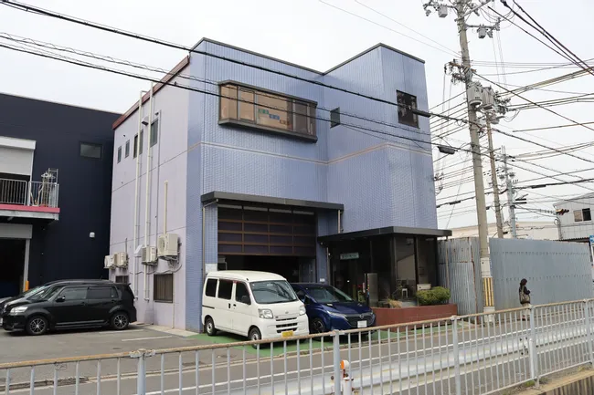 Commercial building exterior in Japan with parked vehicles and overhead utility wires