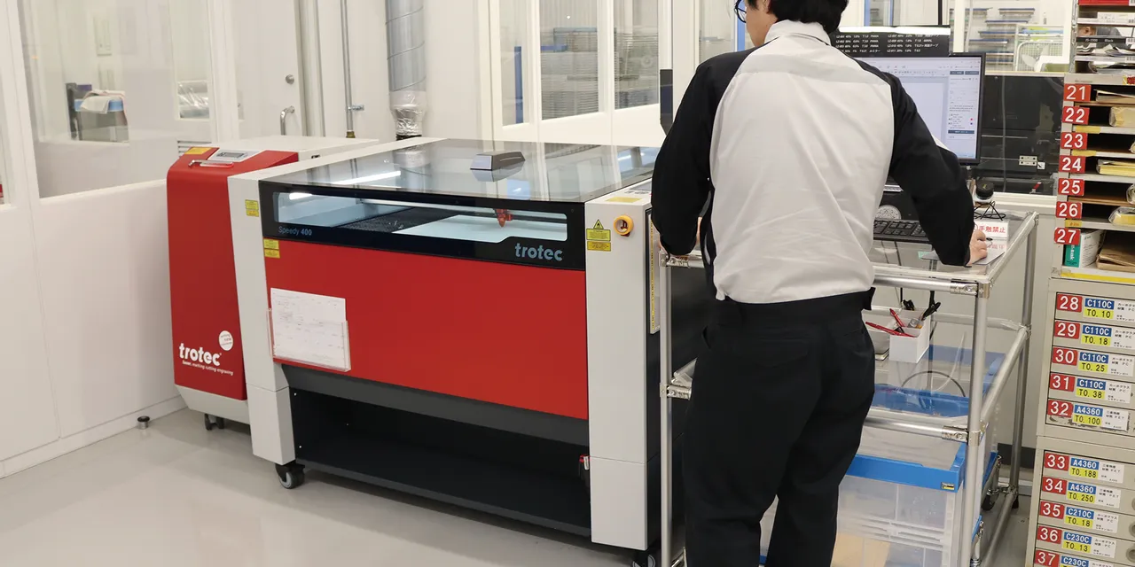 Operator using Trotec Speedy 400 CO₂ laser engraver in a cleanroom environment