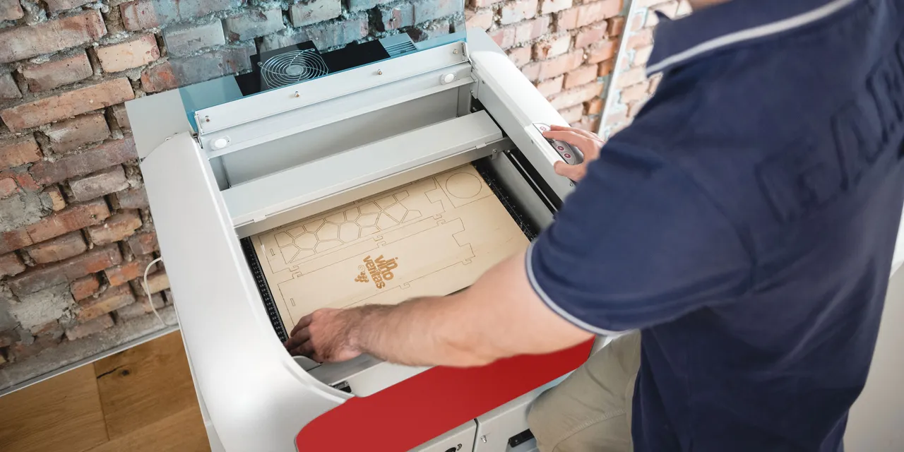 Operator using Trotec Speedy series laser cutter to engrave complex wood design