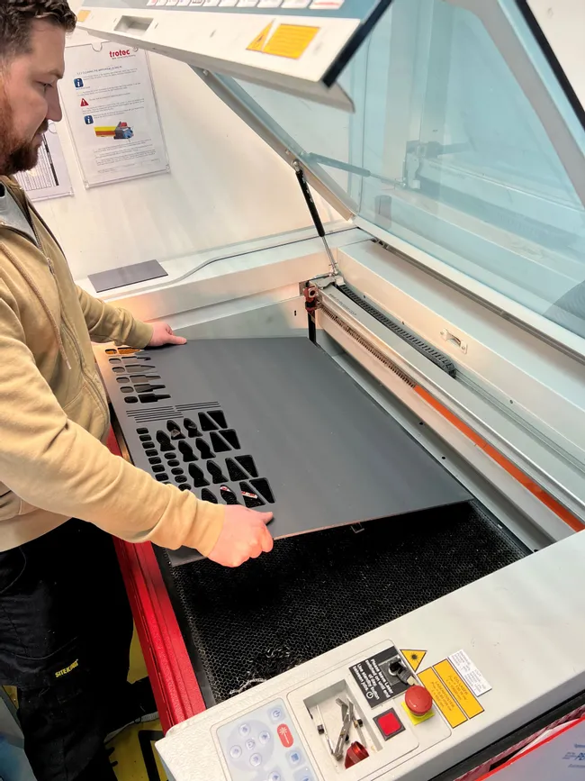 Operator removing cut acrylic sheet from Trotec Speedy series CO₂ laser cutter