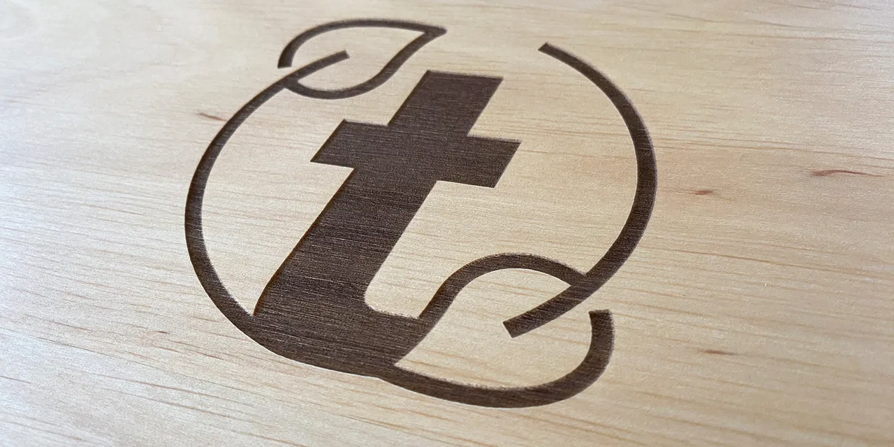 Trotec CO₂ laser engraving logo with leaf design on light wood surface