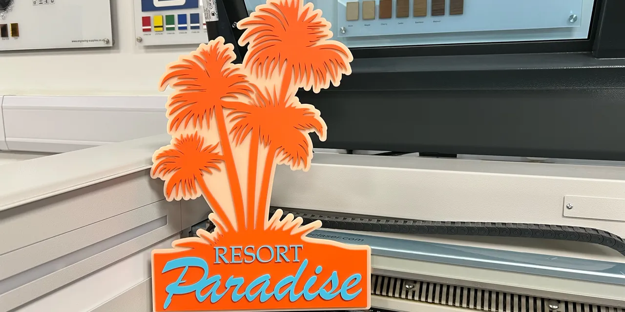 Trotec laser cutter creating layered acrylic Resort Paradise sign with palm tree design