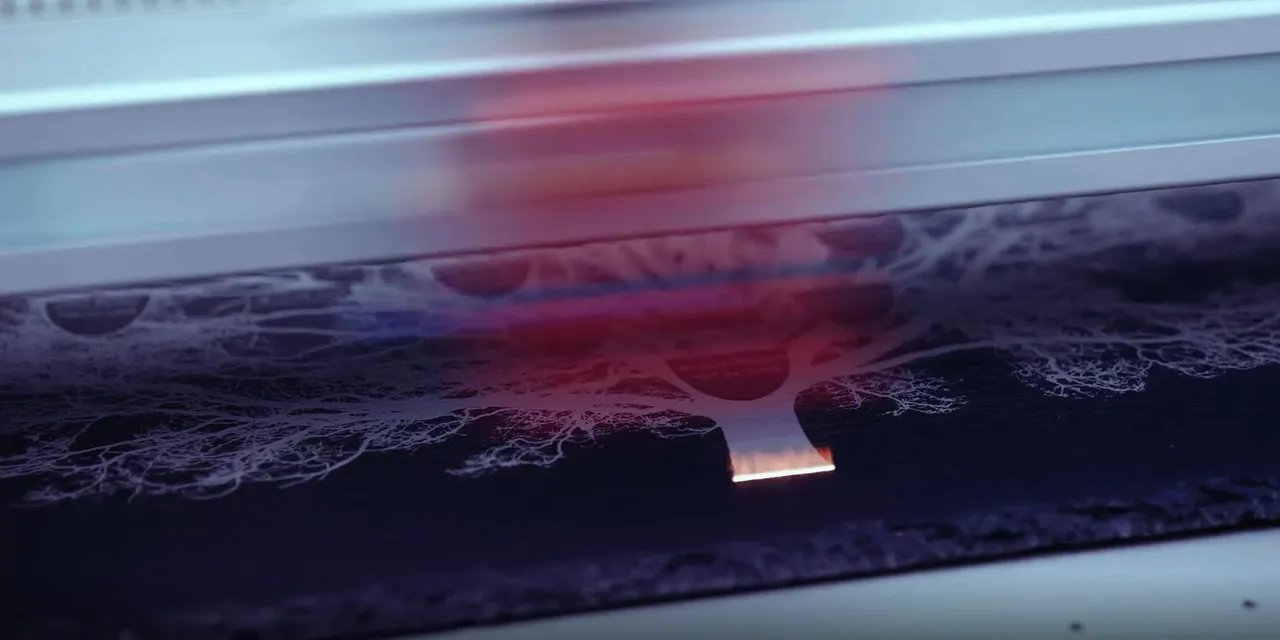 Trotec laser cutter engraving detailed tree design on black material with CO₂ laser