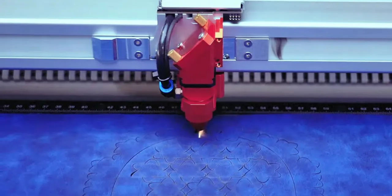 Trotec laser cutter engraving intricate floral pattern on blue material with CO₂ technology