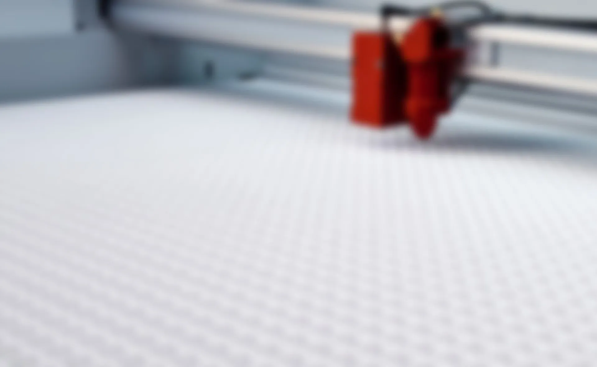 Trotec laser cutter head above honeycomb table in CO₂ engraving machine