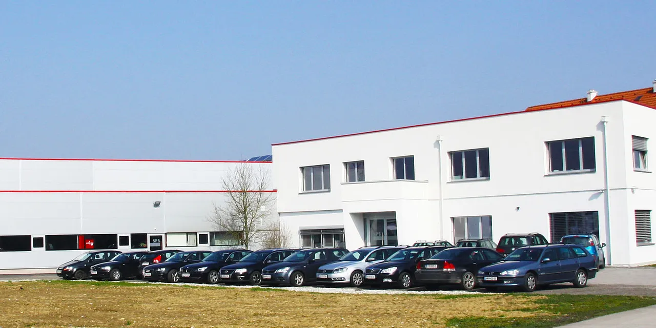 Trotec Laser headquarters with company vehicles parked in front of modern white facility