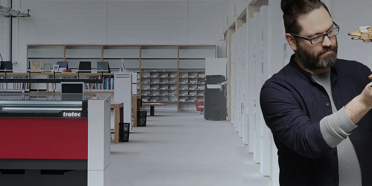 Trotec Speedy 400 flexx laser cutter in modern workspace with man assembling robotic model