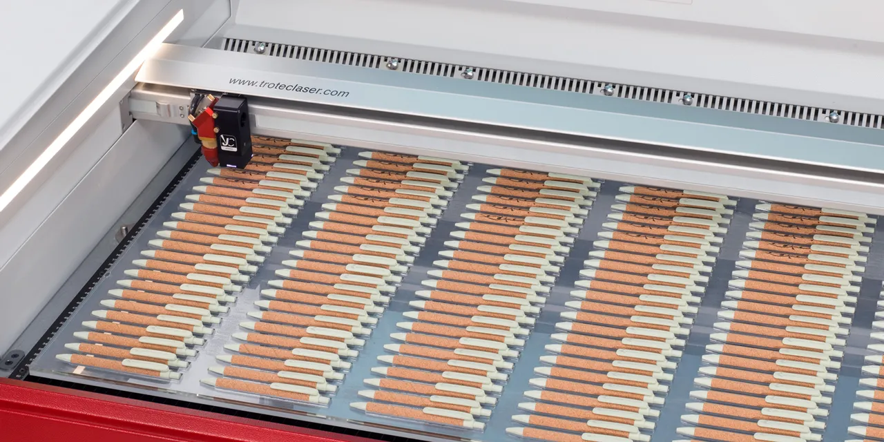 Trotec Speedy laser engraving multiple wooden pens inside CO₂ laser cutter