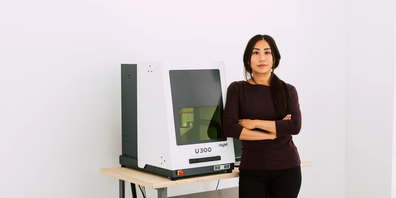 Woman standing beside Trotec U300 laser marking machine in modern workspace
