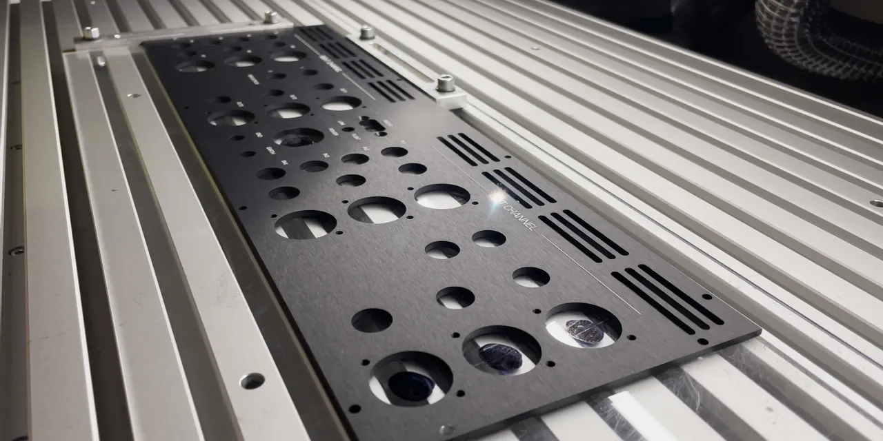 Laser-cut anodized aluminum panel on Trotec laser cutter worktable